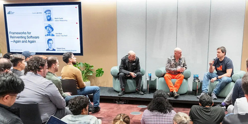 A photo of Gergely, Kent, and myself on the stage. We are all bedazzled by the vibrancy of Kent's trousers